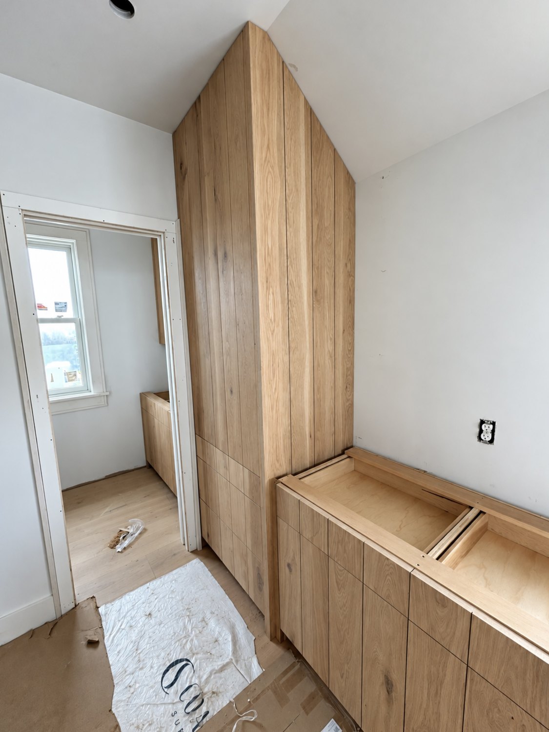 White oak entry bench with drawers and a full-height cabinet
