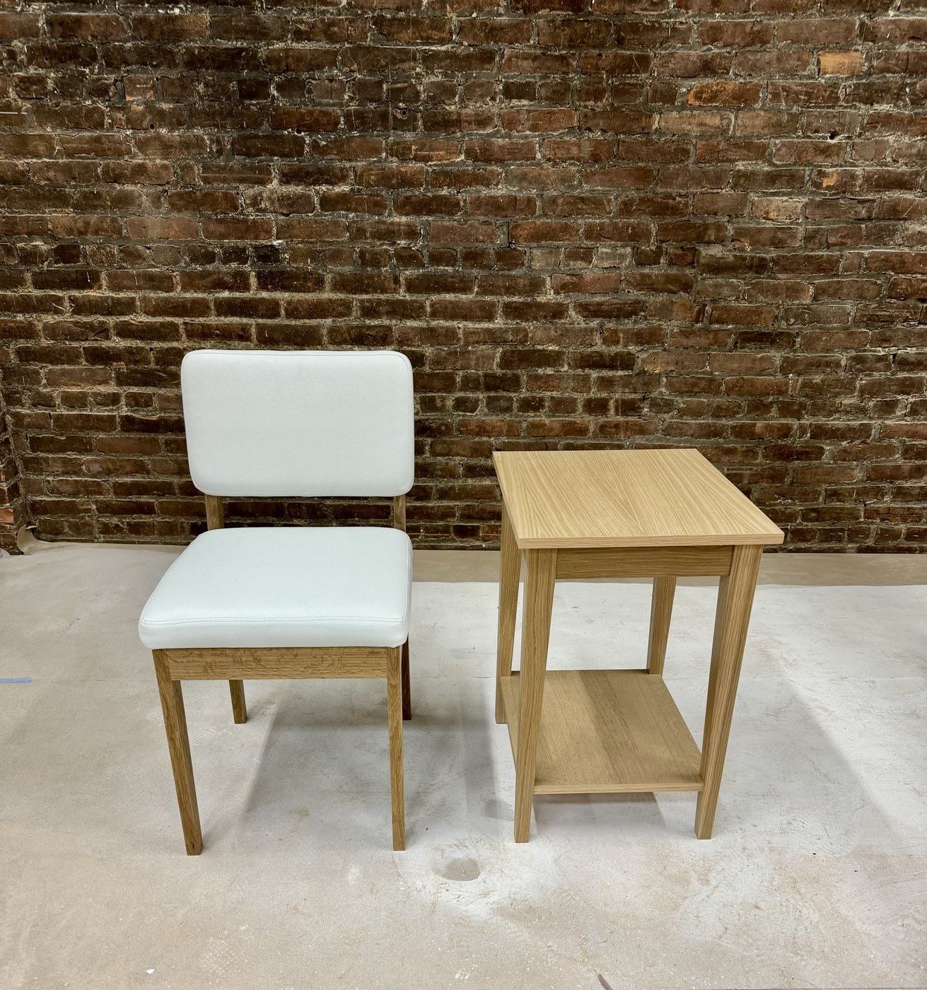 Upholstered side chair beside a small oak table with a lower shelf