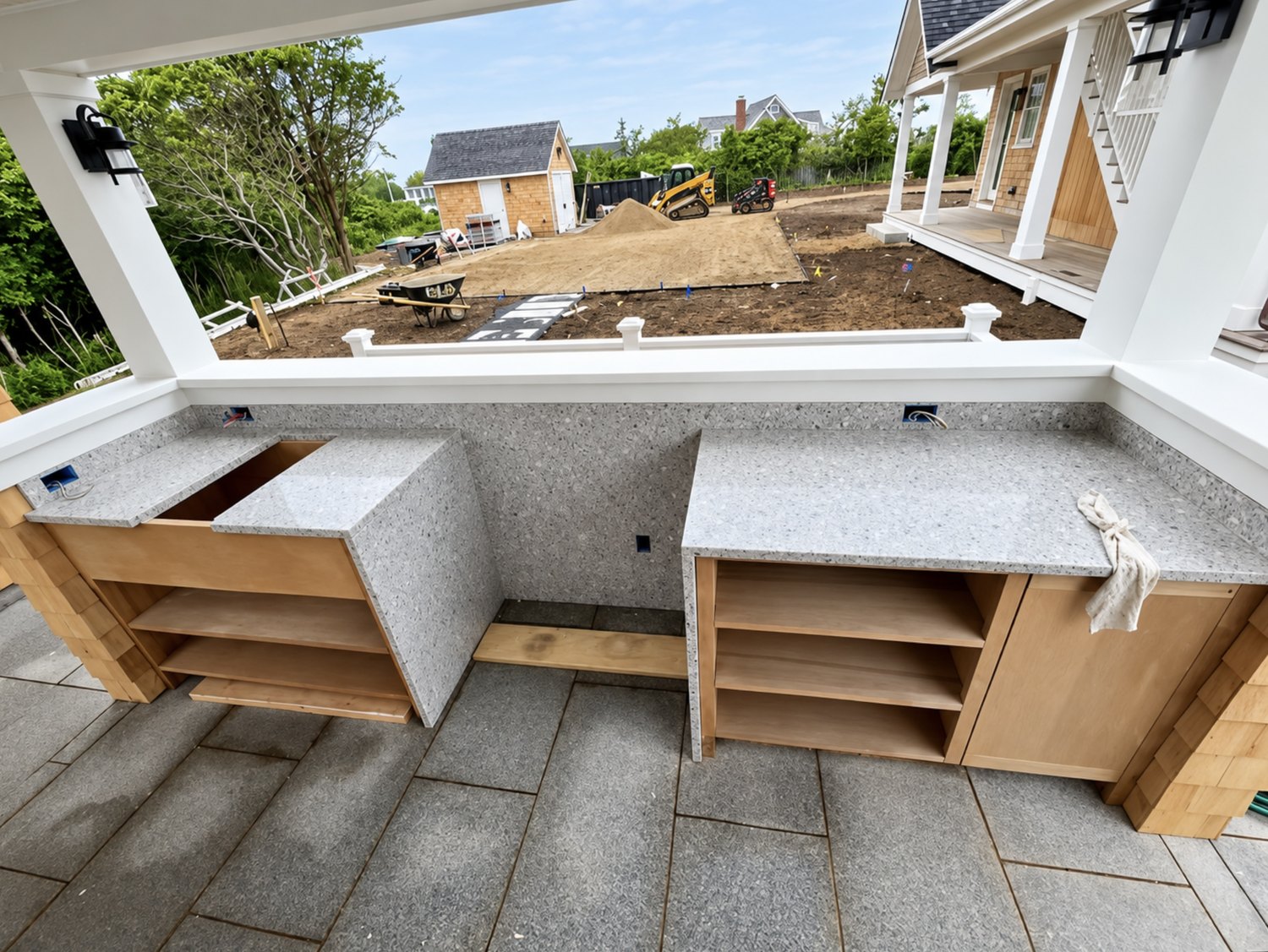 Outdoor kitchen cabinetry being installed under a covered porch