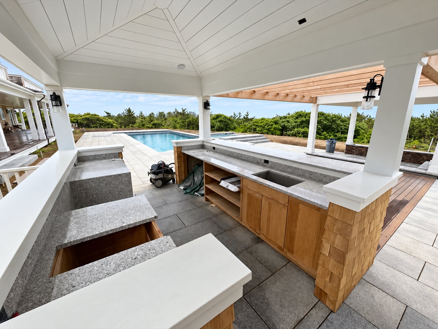 Covered outdoor kitchen and bar beside a pool