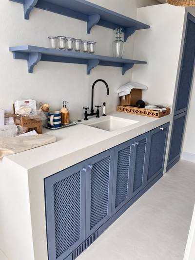 Painted blue kitchen with caned cabinet doors and a white stone counter